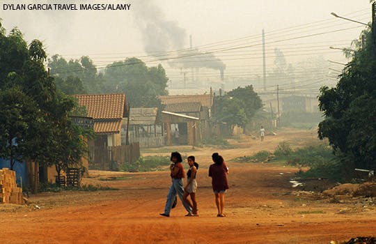 Smoke from fossil fuels is seen in the distance in a town in Brazil